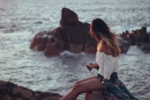 Woman sitting in a stone in Bunbury beach.
