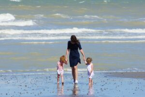 Woman with her two little children walking in the sea